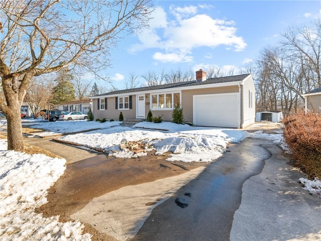 view of front of property featuring driveway, a chimney, and an attached garage