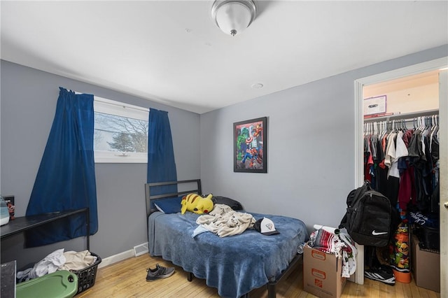 bedroom with a closet, wood finished floors, and baseboards