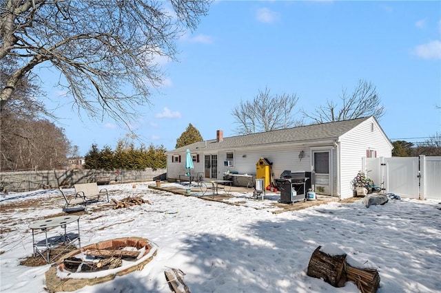 snow covered property with an outdoor fire pit, a gate, and fence