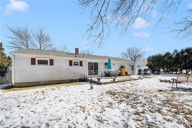 snow covered back of property with a chimney