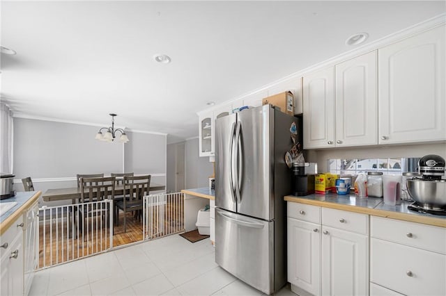 kitchen featuring decorative light fixtures, glass insert cabinets, freestanding refrigerator, white cabinets, and a chandelier