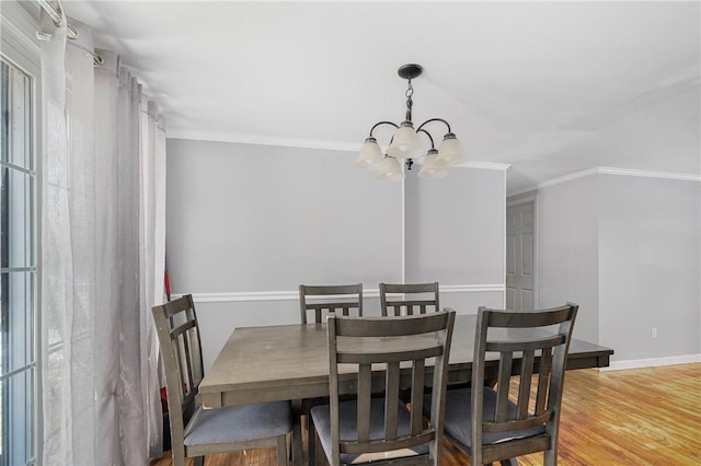 dining area featuring baseboards, a notable chandelier, ornamental molding, and wood finished floors