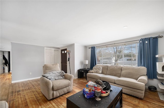 living room featuring baseboards, wood finished floors, and ornamental molding