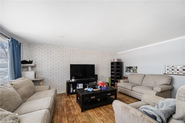 living area with crown molding, brick wall, and wood finished floors