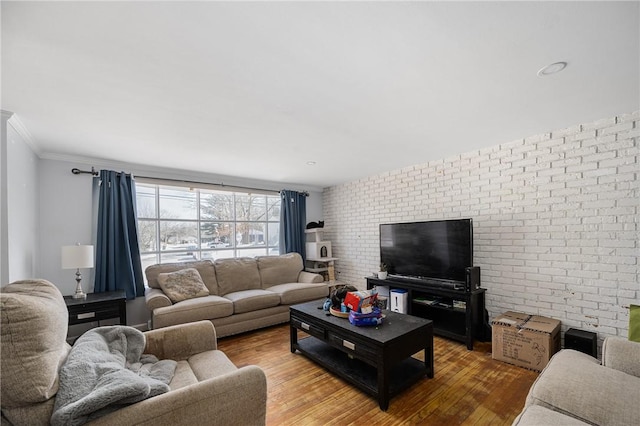 living room with ornamental molding, brick wall, and wood finished floors