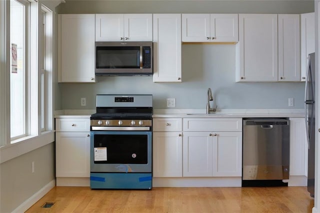 kitchen featuring visible vents, stainless steel appliances, light countertops, white cabinetry, and a sink