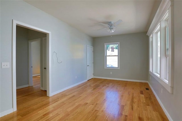 empty room with a ceiling fan, baseboards, and light wood finished floors