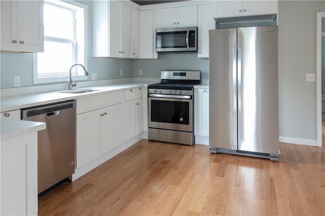 kitchen with white cabinets, appliances with stainless steel finishes, light countertops, and a sink