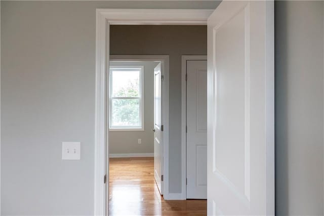 corridor with baseboards and light wood finished floors