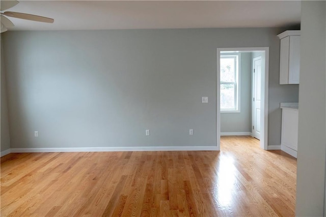 spare room with ceiling fan, light wood finished floors, and baseboards