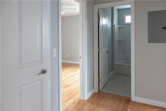 corridor featuring light wood-style floors, electric panel, and baseboards