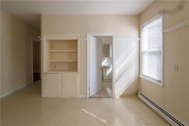 interior space featuring a baseboard heating unit, multiple windows, and light floors