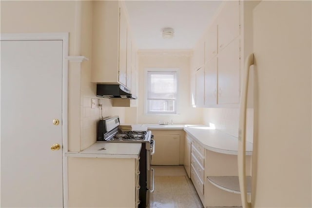 kitchen with crown molding, light countertops, freestanding refrigerator, stainless steel gas range, and under cabinet range hood