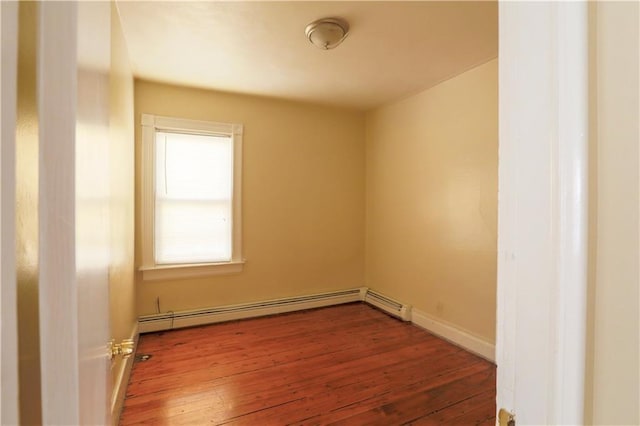 spare room with baseboards, baseboard heating, and wood finished floors