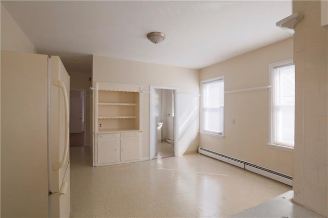 unfurnished bedroom with light floors, a baseboard radiator, and freestanding refrigerator