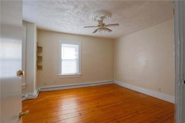 empty room featuring a textured ceiling, ceiling fan, wood finished floors, baseboards, and baseboard heating