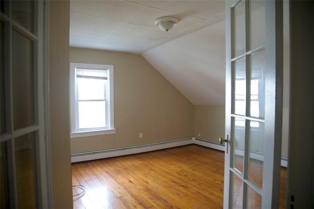 additional living space featuring lofted ceiling, a baseboard heating unit, and wood finished floors