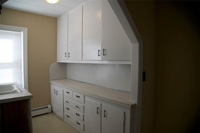 kitchen with a baseboard radiator, white cabinetry, light countertops, and a sink