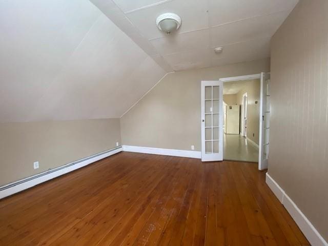 additional living space with lofted ceiling, a baseboard radiator, baseboards, and wood finished floors