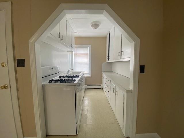 kitchen with white range with gas stovetop, a sink, white cabinetry, light countertops, and baseboard heating