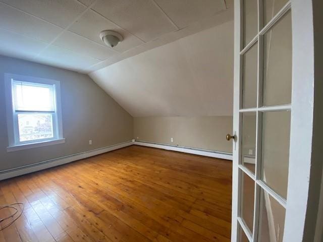 additional living space with lofted ceiling, a baseboard radiator, and wood finished floors