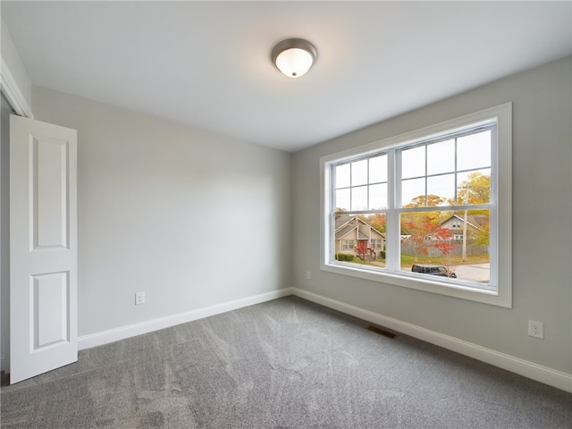 spare room with carpet, visible vents, and baseboards