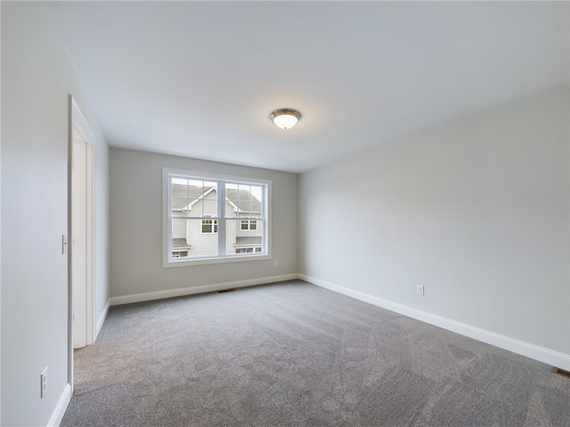 spare room featuring carpet floors and baseboards