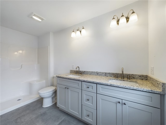 bathroom featuring a shower, a sink, toilet, and double vanity