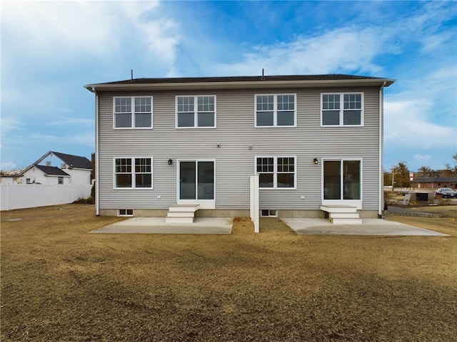 rear view of house featuring entry steps, a patio area, fence, and a lawn