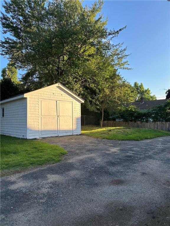 view of shed with fence and aphalt driveway