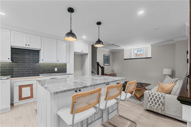 kitchen featuring light stone counters, a kitchen island, white cabinetry, open floor plan, and pendant lighting