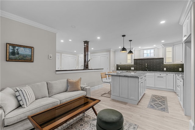 kitchen featuring hanging light fixtures, ornamental molding, open floor plan, white cabinets, and a kitchen island