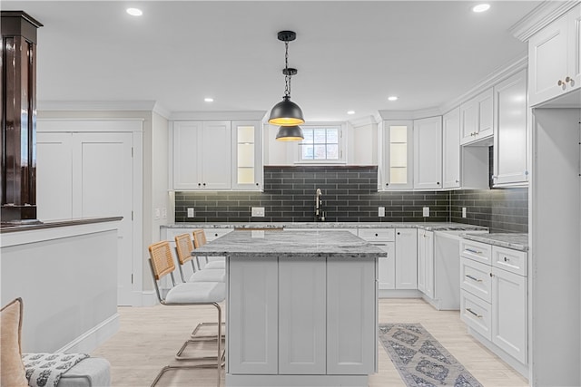 kitchen with white cabinetry, hanging light fixtures, and light stone countertops