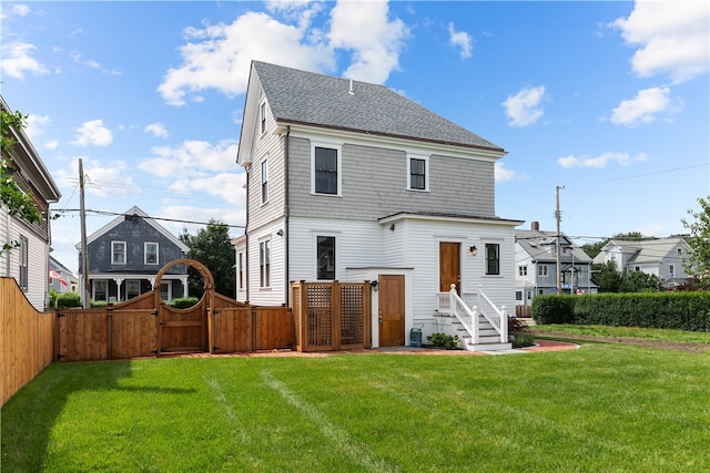 rear view of house featuring a yard, a shingled roof, a gate, fence private yard, and a residential view