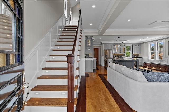 stairway with ornamental molding, wood finished floors, visible vents, and recessed lighting