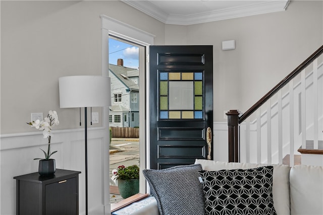 interior space with stairs, ornamental molding, a decorative wall, and wainscoting