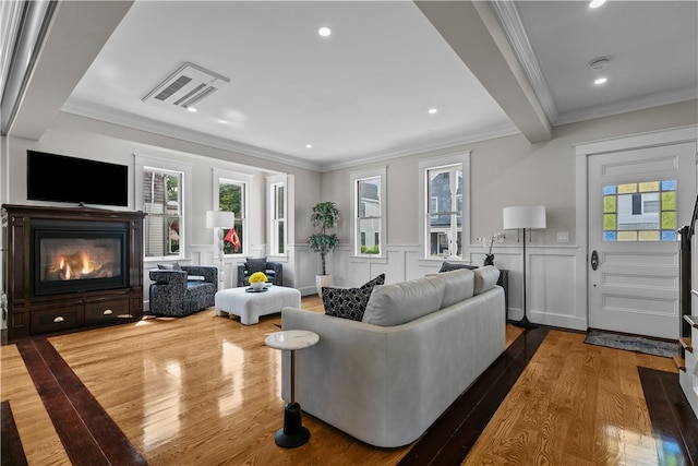 living room with a wainscoted wall, recessed lighting, ornamental molding, a glass covered fireplace, and wood finished floors