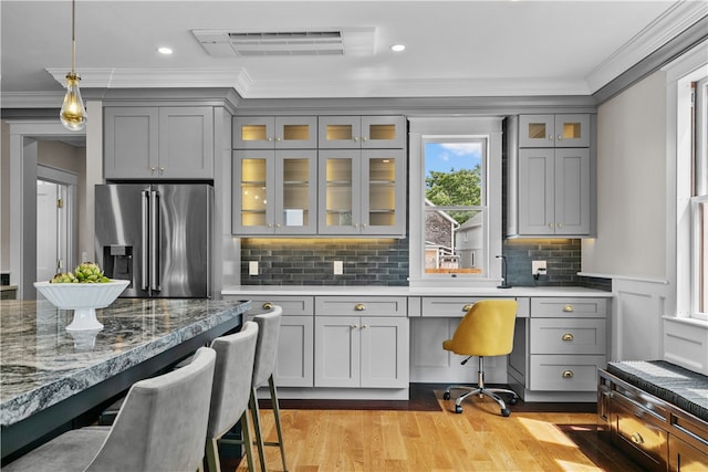 kitchen featuring built in desk, high end refrigerator, a kitchen bar, and glass insert cabinets