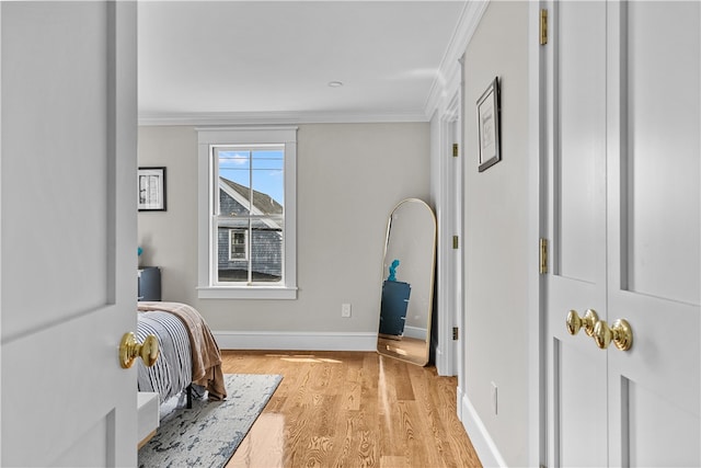 bedroom featuring baseboards, crown molding, and light wood finished floors