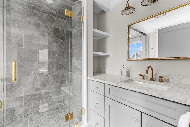 bathroom featuring vanity, a shower stall, visible vents, and crown molding