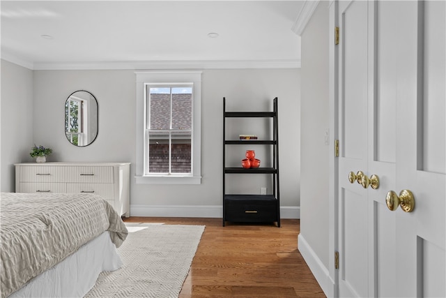 bedroom with light wood finished floors, ornamental molding, and baseboards