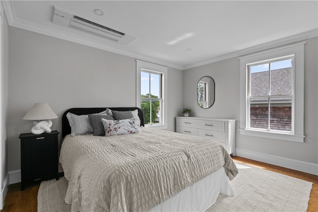 bedroom with baseboards, ornamental molding, and wood finished floors