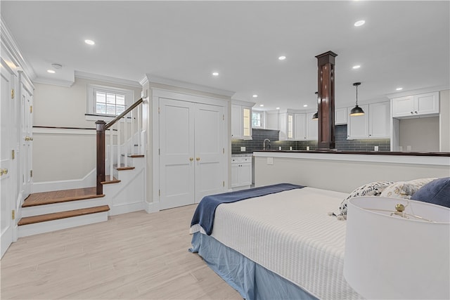 bedroom featuring ornamental molding, recessed lighting, a sink, and light wood-style floors