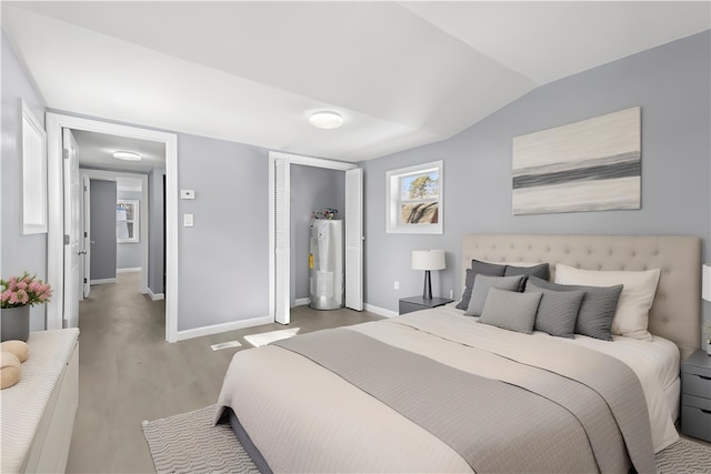 bedroom with lofted ceiling, baseboards, water heater, a closet, and light wood finished floors