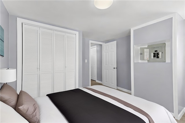 bedroom featuring electric panel, baseboards, and a closet