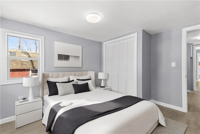 bedroom with light wood finished floors, baseboards, and a closet