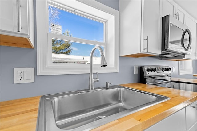 kitchen featuring white cabinets, stainless steel appliances, a sink, and light countertops