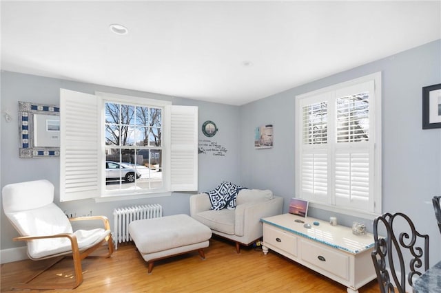 living area featuring radiator heating unit, light wood-style flooring, and baseboards