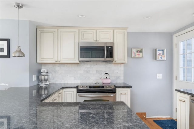 kitchen featuring hanging light fixtures, appliances with stainless steel finishes, cream cabinets, and tasteful backsplash