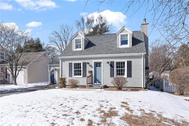 new england style home featuring a garage, a shingled roof, and a chimney